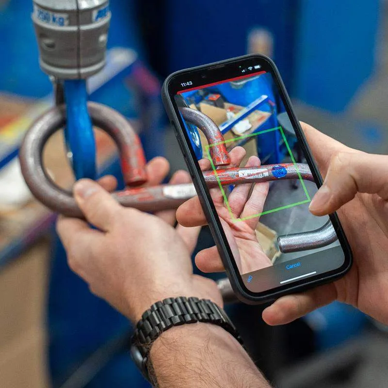 Hände halten einen Anschlagbügel, daneben ein Smartphone mit grünem Erkennungsrahmen auf dem Bildschirm